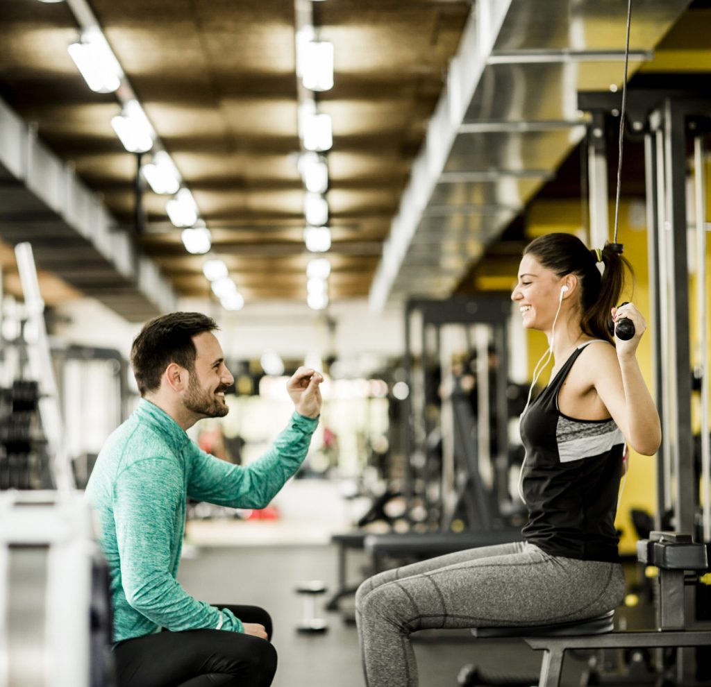 Young woman exercise in a gym with the help of her personal trainer