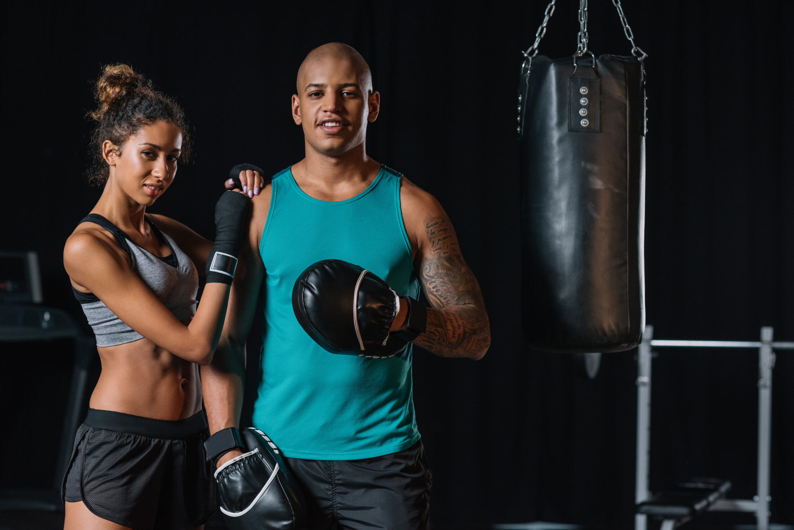 selective focus of african american couple of boxers standing near punching bag at gym